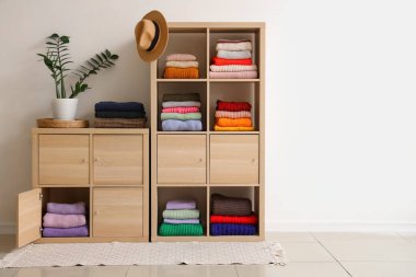 Aydınlık duvarın yanında katlanmış kış süveterleri olan çekmeceler.