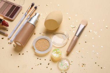 Bej arka planda parlaklık, payet, makyaj ürünleri ve aksesuarlı kompozisyon