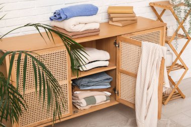 Klozet, kitaplar ve beyaz tuğla duvarın yanında katlanmış giysiler, yakın plan.