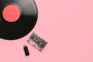 Pembe arka planda vinil disk, kaset ve USB flaş bellek. Evrim kavramı