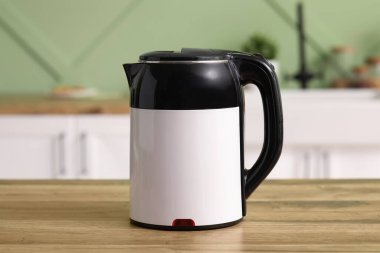 Modern electric kettle on wooden table in kitchen