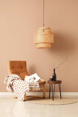 Koltuk ve kahve masası. Odada kahverengi duvarın yanında şişe var.