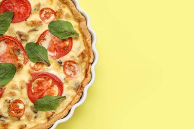 Sarı arka planda ıspanak yapraklı lezzetli domatesli tart, yakın plan.