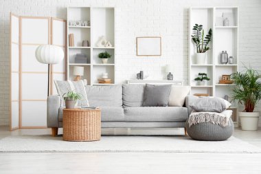 Comfortable grey sofa, pouf and table in interior of living room