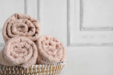 Temiz havluları beyaz duvara yapıştırılmış hasır sepet.