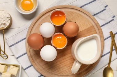 Tahtayı taze tavuk yumurtasıyla kesmek, süt sürahisi ve un hafif ahşap masada.