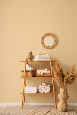 Raflar temiz yatak çarşafları, pamuk çiçekleri ve bej duvarın yanındaki ev dekoruyla dolu.