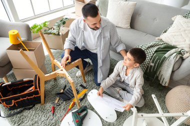 Baba ve oğlu talimatlarla evde mobilya monte ediyorlar.