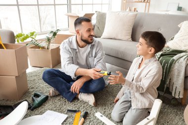 Tornavidalı baba ve oğlu evde mobilya montajı yapıyor.