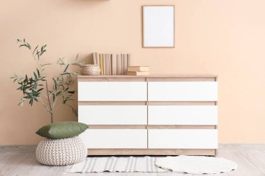 Odanın iç tarafındaki bej duvarın yakınındaki çekmecelerin üzerindeki sandık ve kitaplar.