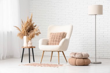 Aydınlık oturma odasının içinde koltuk, masa ve lamba var.