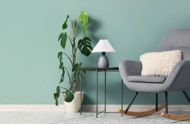 Sallanan koltuk, masa ve palmiye bitkisi olan oturma odasının içinde.