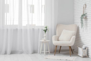 Oturma odasının içinde vazoda koltuk, masa ve yapay çiçekler var.