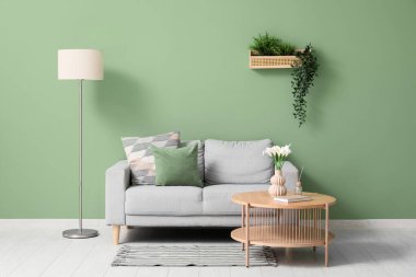 Oturma odasının içinde kanepe, masa ve yapay bitkiler var.