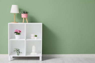 Yapay çiçekli raf ünitesi ve yeşil duvarın yanındaki oda.