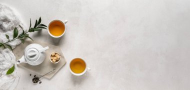 Bardaklar dolusu içecek, çaydanlık ve şeker. Arka planda metin ve üst görünüm için yer var.