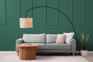 Modern oturma odasının içinde rahat gri kanepe, sehpa ve lamba var.