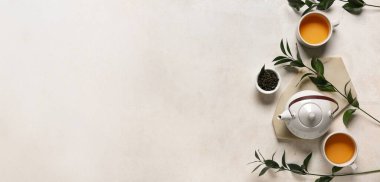 Çaydanlık, bardak ve kuru yapraklarla metin ve üst görünüm için alanı olan ışık arkaplanı bileşimi