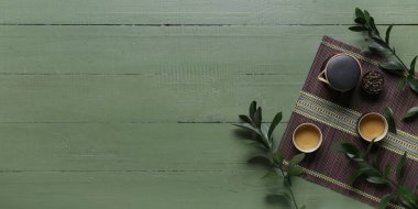 Bambu hasırı, çaydanlık ve fincanlar yeşil ahşap zemin üzerinde metin için alan, üst görünüm
