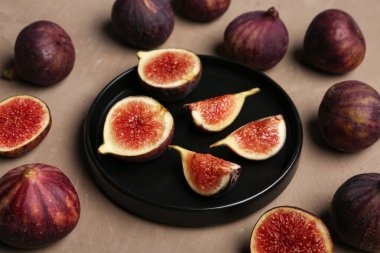 Kahverengi arka planda kesilmiş taze incir tabağı