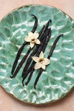 Aromatik vanilyalı tabak ve pembe arka planda çiçekler.