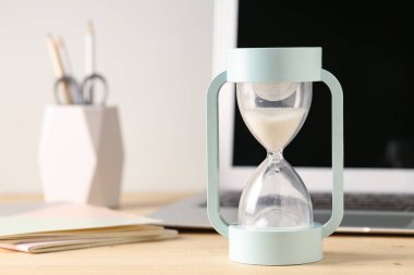 Hourglass and laptop on table. Time management concept