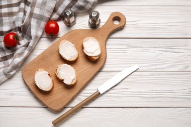 İşlenmiş peynirli lezzetli bruschetta ve beyaz ahşap arka planda taze domates kesme tahtası.