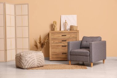 Oturma odasının içinde koltuk, katlanan ekran ve kahverengi duvarın yanında tuvalet.