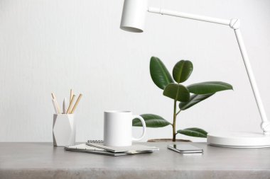 Ofisteki kalem tutacağının yanındaki masada beyaz seramik bardak.