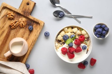 Beyaz arka planda sağlıklı mısır gevreği, yoğurt ve böğürtlen kâsesi.