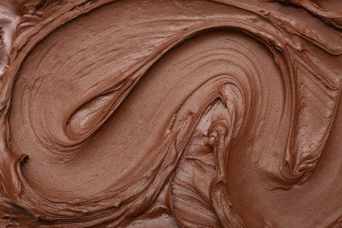 Arka planda erimiş sütlü çikolata kıvrımı var.