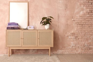 İçinde retro telefon olan mor kıyafetler yığını ve odadaki grunge pembe duvarın yanında klozet var.