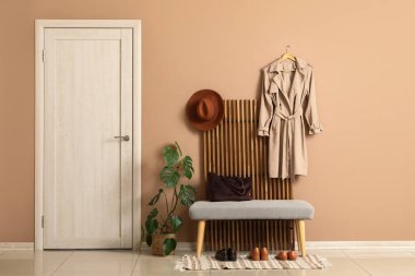 Katlanan ekran, ev bitkisi ve bank modern koridorun içindeki bej duvarın yanında.