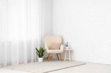 Koltuk, masa ve bitkiler ışık perdesinin yanındaki odada.