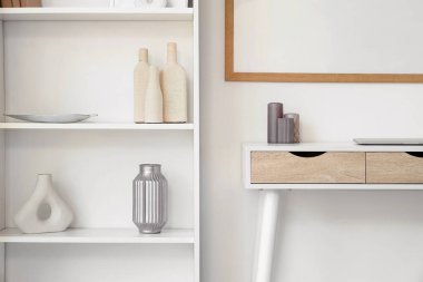 Raflarda şık dekorları ve masasında gri mumları olan bir ünite.