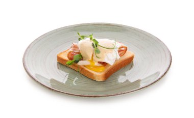 Pastırmalı Benedict yumurtası ve beyaz arka planda mikro yeşil.