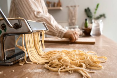 Masada hamurlu makarna makinesi mutfakta genç bir kadına karşı, yakın plan.