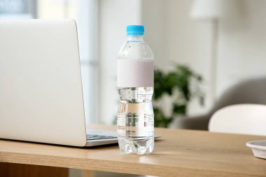 Bir şişe su ve modern laptop masadaki, yakın plan.