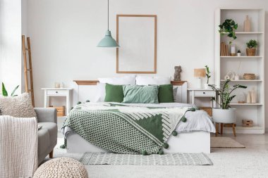 Konforlu yatağı, raf ünitesi ve çiçekleri olan hafif yatak odasının içi.