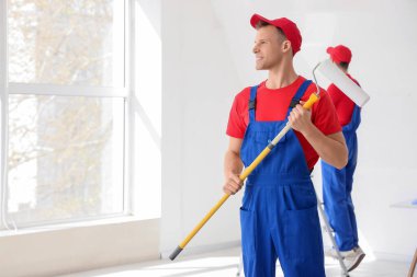 Odada boya silindiri olan erkek dekoratör.
