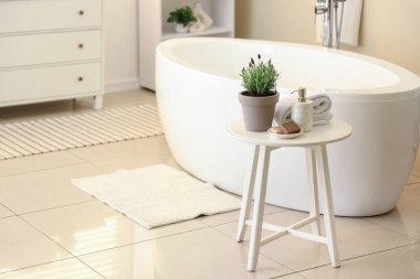 Lavabonun yanındaki kahve masasında lavanta çiçekleri, havlu ve kozmetik ürünler var.