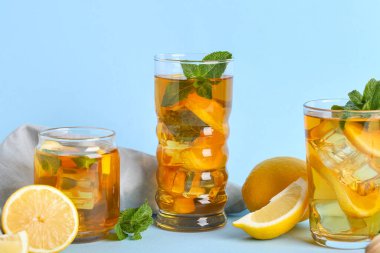 Mavi arka planda nane ve turunçgil meyveli limonlu buzlu çay.