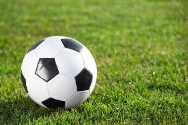 Yeşil stadyum çimlerinde futbol topu, yakın plan.