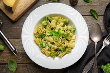 Tahta zemin üzerinde brokoli ve fesleğen yapraklı lezzetli fusilli makarna.