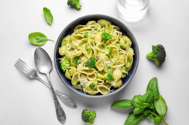 Beyaz arka planda brokoli, peynir ve fesleğen yapraklı bir kase lezzetli conchigile rigate makarna.
