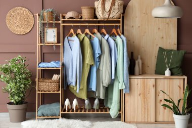 Raflar ve raflar kahverengi duvarın yanında şık giysilerle dolu.