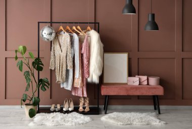 Rafta, bankta giysiler, aksesuarlar ve kahverengi duvarın yanındaki disko topu.