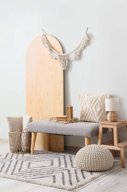 Gri bank, puf, katlanan ekran ve merdiven, koridorun iç tarafındaki beyaz duvarın yanında.