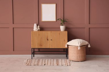 Çekmeceler, masa ve puf oturma odasının içindeki kahverengi duvarın yanında.