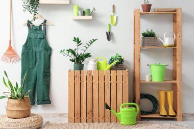 Bahçıvan üniforması, raf ünitesi ve bitkilerle dolu bir atölye.